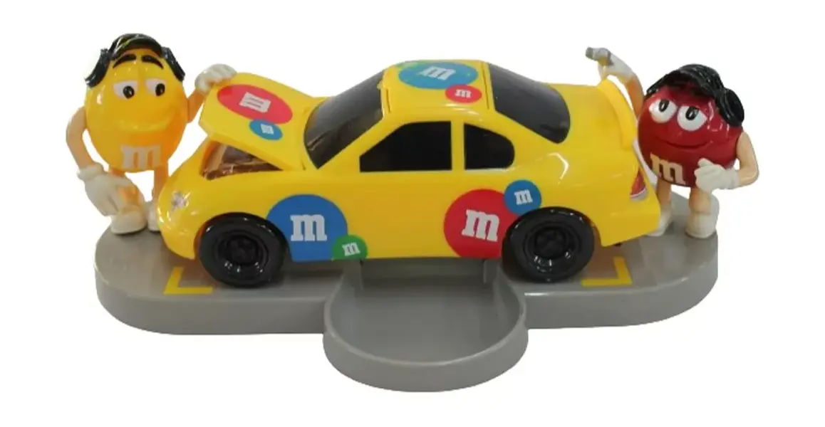 Foto de um(a) Dispenser M & M carro de corrida, da categoria de Brinquedos e Hobbies. Dispenser M&M em formato de carro com dois bonecos em cada lateral, abertura do dispenser fica no teto. Medidas carro 9A x... Mostrado de uma perspectiva diferente. Vendido no marketplace Trésors.