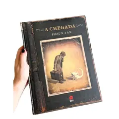 Foto de um(a) Livro de ilustrações decorativo em capa dura, da categoria de Livros. Livro capa dura, de 2021, em português, mas ele é somente com ilustrações. Conta história de imigrantes. Leves marcas do... Vendido no marketplace Trésors.