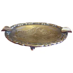 Foto de um(a) Cinzeiro Ornamentado em Metal, da categoria de Cinzeiros. Uma peça que exala sofisticação e história. Este cinzeiro oval em metal apresenta um rico trabalho de ornamentação, com... Vendido no marketplace Trésors.