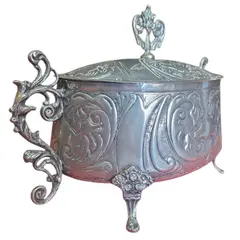 Foto de um(a) Antiga Terrina Decorativa em Metal Prateado, da categoria de Cachepot. Elegante recipiente oval com tampa, ricamente adornado com motivos florais e volutas em relevo. Uma peça de destaque para... Vendido no marketplace Trésors.