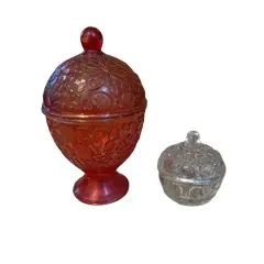 Foto de um(a) 2 belas bomboniéres, sendo uma da Avon anos 60, da categoria de Garrafas, potes e jarros. Duas belas bombonières de vidro decorativas (potes com tampa), sendo a vermelha um modelo clássico de colecionador da marca... Vendido no marketplace Trésors.