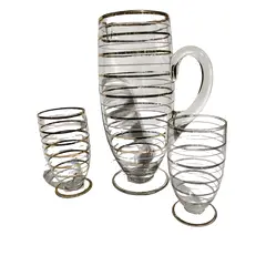 Foto de um(a) Conjunto Jarra e Copos em Vidro e Ouro Anos 50, da categoria de Jogos de taças e copos. Jarra de vidro com filetes em ouro da década de 1950, com dois copos. A: 25,5 cm / Diâmetro: 10 cmCopos: A 13 cm /... Vendido no marketplace Trésors.