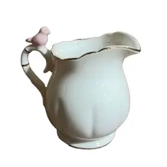 Foto de um(a) Cremeira Passarinho Wolff, Década de 2010, da categoria de Cremeiras. Cremeira em porcelana branca lisa levemente canelada, com filete em ouro na borda e alça e detalhe de passarinho na cor... Vendido no marketplace Trésors.