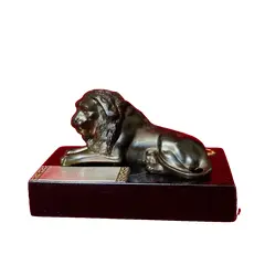 Foto de um(a) Troféu Leão do Ano, 71/72, da categoria de Escultura. Troféu Lions 1971/1972 - Leão do Ano. Em bronze com base de granito preto. A: 7 cm / L: 12 cm / P: 7,4 cm peso: 738 g. Vendido no marketplace Trésors.