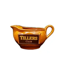 Foto de um(a) Molheira Escocesa Tillers Club, Década de 1980, da categoria de Cremeiras. Molheira com logo da tillers club dos anos 1980 em porcelana na cor âmbar.A: 10 cm L: 15,5 cm L com alça: 19,4 cm P: 9 cm... Vendido no marketplace Trésors.