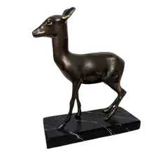 Foto de um(a) Escultura Cervo em Bronze, da categoria de Escultura. Cervo em bronze com base em madeira marmorizada, década de 1930. A: 24cm / P: 6cm / L: 19cm Base: 21 x 9 x 2cm. Vendido no marketplace Trésors.