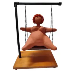 Foto de um(a) Escultura Feminina em Terracota, Peça Única, da categoria de Escultura. Escultura feminina em terracota no balanço, cabelos são de contas na cor coral, balanço em ferro com madeira e base com pés... Vendido no marketplace Trésors.