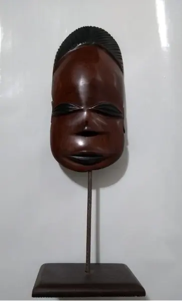 Foto de um(a) Máscara Africana em Madeira, da categoria de Modelos e estatuetas. Máscara africana esculpida em madeira com base também em madeira. Peso: 272g A: 32cm L: 11cm P: 8cm. Mostrado de uma perspectiva diferente. Vendido no marketplace Trésors.