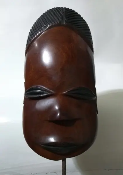 Foto de um(a) Máscara Africana em Madeira, da categoria de Modelos e estatuetas. Máscara africana esculpida em madeira com base também em madeira. Peso: 272g A: 32cm L: 11cm P: 8cm. Mostrado de uma perspectiva diferente. Vendido no marketplace Trésors.