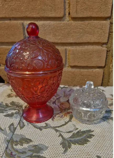 Foto de um(a) 2 belas bomboniéres, sendo uma da Avon anos 60, da categoria de Garrafas, potes e jarros. Duas belas bombonières de vidro decorativas (potes com tampa), sendo a vermelha um modelo clássico de colecionador da marca... Mostrado de uma perspectiva diferente. Vendido no marketplace Trésors.