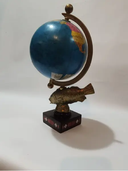 Foto de um(a) Globo Terrestre Latão e Marchetaria anos 70, da categoria de Globos. Globo terrestre de mesa com globo giratório e envelhecido com base de peixe em latão e madeira com marchetaria adesivada... Mostrado de uma perspectiva diferente. Vendido no marketplace Trésors.