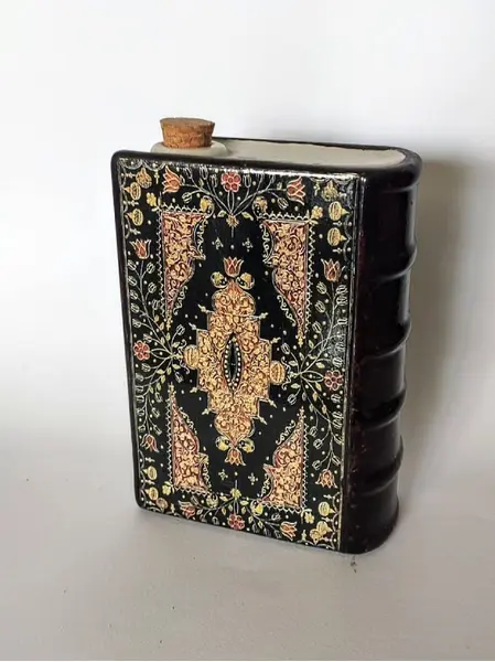 Foto de um(a) Livro Decorativo em Porcelana Anos 60, da categoria de Objetos decorativos. Livro fake em porcelana policromada para bebidas com tampa de rolha, capa e contra capa trabalhada, década de 1960. A: 17 cm... Mostrado de uma perspectiva diferente. Vendido no marketplace Trésors.