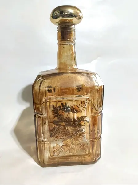 Foto de um(a) Garrafa Âmbar 70'S, da categoria de Garrafas, potes e jarros. Garrafa âmbar com pintura floral em dourado, década de 1970.A: 24,5 cm L: 11 cm P: 8 cm / peso: 765 g. Mostrado de uma perspectiva diferente. Vendido no marketplace Trésors.