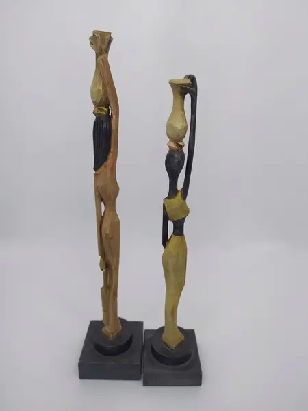 Foto de um(a) Par de esculturas africanas em madeira, da categoria de Escultura. Par de esculturas africanas em madeira, pintada à mão, retratando mulheres carregando baldes. Mede A: 31cm. Mostrado de uma perspectiva diferente. Vendido no marketplace Trésors.