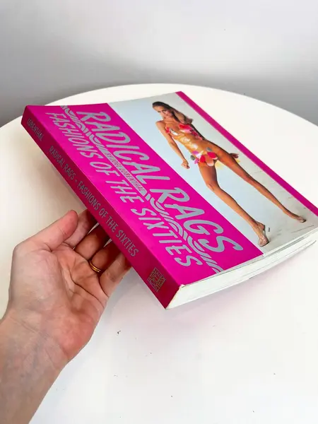 Foto de um(a) Livro Radical Rags - Fashions of the Sixties 1990, da categoria de Livros. Livro capa brochura de 1990, em inglês, sobre a moda da seca de 1960. Leves marcas do tempo. 256 páginas. Mostrado de uma perspectiva diferente. Vendido no marketplace Trésors.