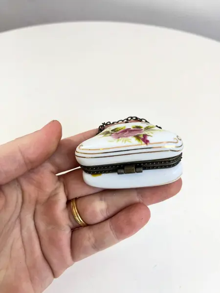 Foto de um(a) ​Porta pílulas em porcelana e metal - formato bolsinha, da categoria de Outros colecionáveis. Porta pílulas em porcelana e metal no formato de bolsinha. Mínimas marcas do tempo e uso. Medidas: 6x3cm. Mostrado de uma perspectiva diferente. Vendido no marketplace Trésors.