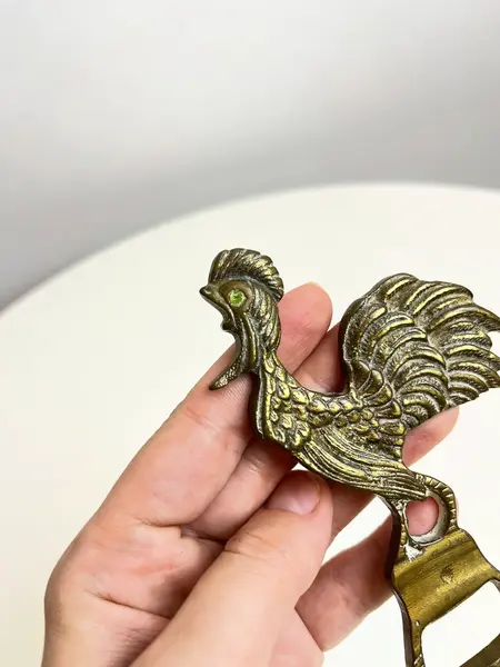 Foto de um(a) ​Abridor de garrafas em bronze, da categoria de Abridores de garrafas. Abridor de garrafas em bronze com detalhe em strass. Marcas do tempo e uso como nas fotos. Medidas: 12x5cm. Mostrado de uma perspectiva diferente. Vendido no marketplace Trésors.