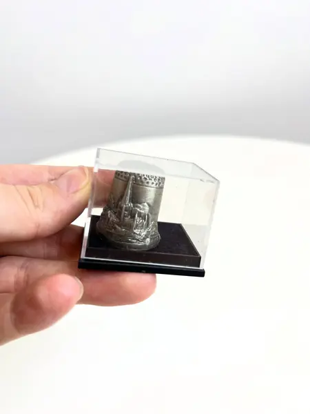Foto de um(a) ​Dedal em chumbo na caixinha de acrílico, da categoria de Outros colecionáveis. Dedal em chumbo na caixinha de acrílico. Souvenir inglês. Medidas caixinha: 4x3,5cm. Mostrado de uma perspectiva diferente. Vendido no marketplace Trésors.