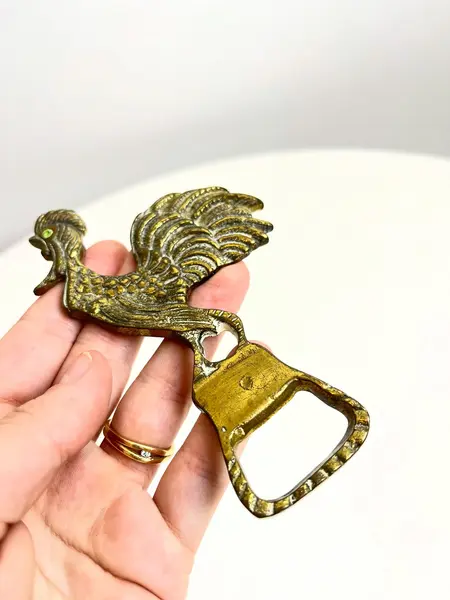 Foto de um(a) ​Abridor de garrafas em bronze, da categoria de Abridores de garrafas. Abridor de garrafas em bronze com detalhe em strass. Marcas do tempo e uso como nas fotos. Medidas: 12x5cm. Mostrado de uma perspectiva diferente. Vendido no marketplace Trésors.