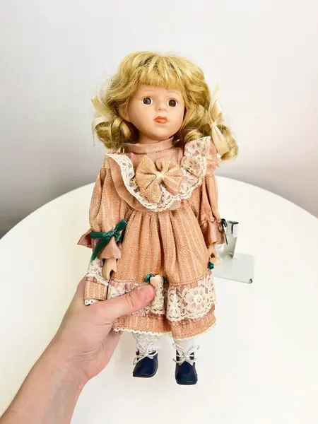 Foto de um(a) ​Boneca de porcelana, da categoria de Brinquedos e Hobbies. Boneca de porcelana com leves marcas do tempo e uso. Com suporte. Medidas: 30x16cm. Mostrado de uma perspectiva diferente. Vendido no marketplace Trésors.