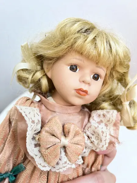 Foto de um(a) ​Boneca de porcelana, da categoria de Brinquedos e Hobbies. Boneca de porcelana com leves marcas do tempo e uso. Com suporte. Medidas: 30x16cm. Mostrado de uma perspectiva diferente. Vendido no marketplace Trésors.