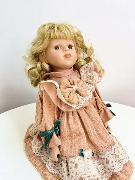 Foto de um(a) ​Boneca de porcelana, da categoria de Brinquedos e Hobbies. Boneca de porcelana com leves marcas do tempo e uso. Com suporte. Medidas: 30x16cm. Mostrado de uma perspectiva diferente. Vendido no marketplace Trésors.