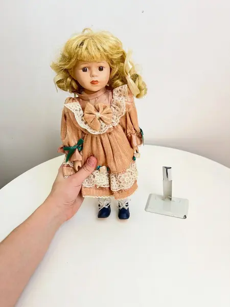 Foto de um(a) ​Boneca de porcelana, da categoria de Brinquedos e Hobbies. Boneca de porcelana com leves marcas do tempo e uso. Com suporte. Medidas: 30x16cm. Mostrado de uma perspectiva diferente. Vendido no marketplace Trésors.