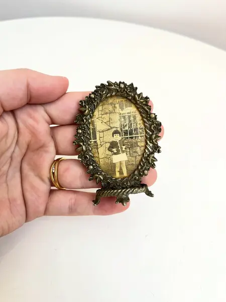 Foto de um(a) Pequeno porta retrato em metal, da categoria de Porta retratos. Pequeno porta retrato em metal. Marcas do tempo e uso como nas fotos. Medidas: 7x5cm. Mostrado de uma perspectiva diferente. Vendido no marketplace Trésors.