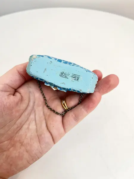 Foto de um(a) ​Bolsinha colecionável em resina, da categoria de Outros colecionáveis. Bolsinha colecionável em resina com alça em corrente metálica. Apresenta desgastes na pintura como nas fotos. Medidas: 6x8cm. Mostrado de uma perspectiva diferente. Vendido no marketplace Trésors.
