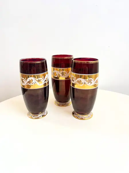 Foto de um(a) ​Trio de copos altos de vidro da década de 50, da categoria de Copos. Trio de copos altos de vidro da década de 50, pintados em bordô, dourado e branco. Marcas do tempo e uso e um com mínimo... Mostrado de uma perspectiva diferente. Vendido no marketplace Trésors.
