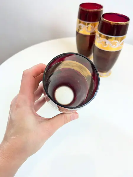 Foto de um(a) ​Trio de copos altos de vidro da década de 50, da categoria de Copos. Trio de copos altos de vidro da década de 50, pintados em bordô, dourado e branco. Marcas do tempo e uso e um com mínimo... Mostrado de uma perspectiva diferente. Vendido no marketplace Trésors.