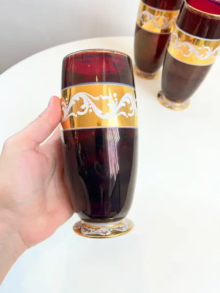 Foto de um(a) ​Trio de copos altos de vidro da década de 50, da categoria de Copos. Trio de copos altos de vidro da década de 50, pintados em bordô, dourado e branco. Marcas do tempo e uso e um com mínimo... Mostrado de uma perspectiva diferente. Vendido no marketplace Trésors.