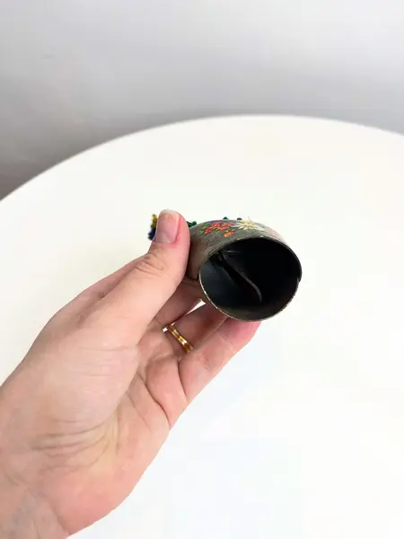 Foto de um(a) Sino suiço em metal, da categoria de Memorabilia de viagem & souvenir. Sino suíço em metal estampado, couro e lã. Marcas do tempo e uso como nas fotos. Medidas: 16x6cm. Mostrado de uma perspectiva diferente. Vendido no marketplace Trésors.