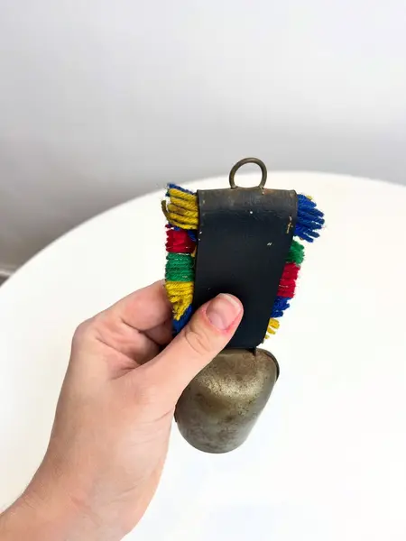 Foto de um(a) Sino suiço em metal, da categoria de Memorabilia de viagem & souvenir. Sino suíço em metal estampado, couro e lã. Marcas do tempo e uso como nas fotos. Medidas: 16x6cm. Mostrado de uma perspectiva diferente. Vendido no marketplace Trésors.