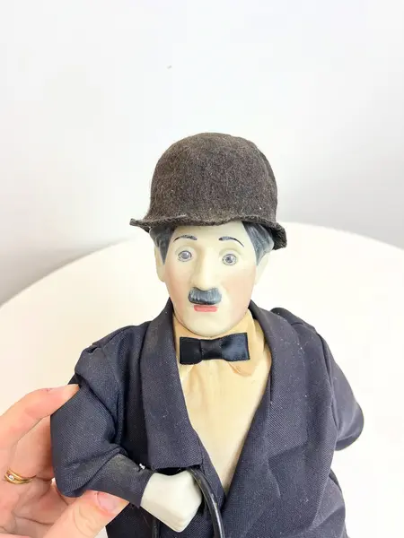 Foto de um(a) ​Boneco Charles Chaplin em porcelana e tecido, da categoria de Bonecos de arte. Boneco do Charles Chaplin em porcelana e tecido, com bengala em metal e chapéu em feltro. Marcas do tempo e uso mas sem nada... Mostrado de uma perspectiva diferente. Vendido no marketplace Trésors.