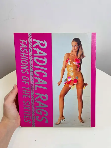 Foto de um(a) Livro Radical Rags - Fashions of the Sixties 1990, da categoria de Livros. Livro capa brochura de 1990, em inglês, sobre a moda da seca de 1960. Leves marcas do tempo. 256 páginas. Mostrado de uma perspectiva diferente. Vendido no marketplace Trésors.