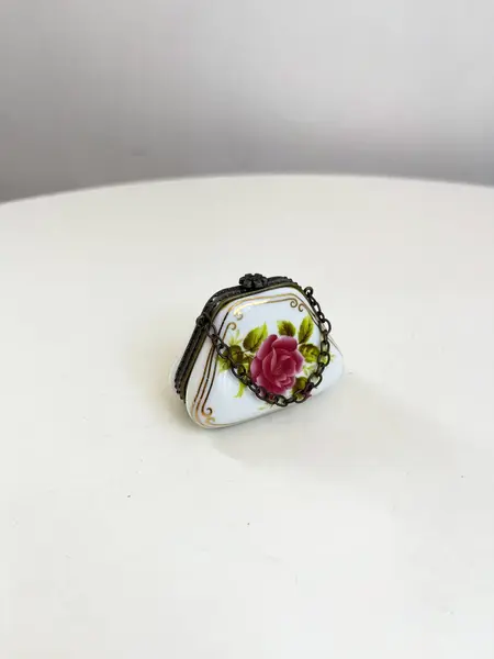 Foto de um(a) ​Porta pílulas em porcelana e metal - formato bolsinha, da categoria de Outros colecionáveis. Porta pílulas em porcelana e metal no formato de bolsinha. Mínimas marcas do tempo e uso. Medidas: 6x3cm. Mostrado de uma perspectiva diferente. Vendido no marketplace Trésors.