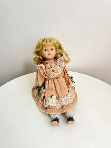 Foto de um(a) ​Boneca de porcelana, da categoria de Brinquedos e Hobbies. Boneca de porcelana com leves marcas do tempo e uso. Com suporte. Medidas: 30x16cm. Mostrado de uma perspectiva diferente. Vendido no marketplace Trésors.