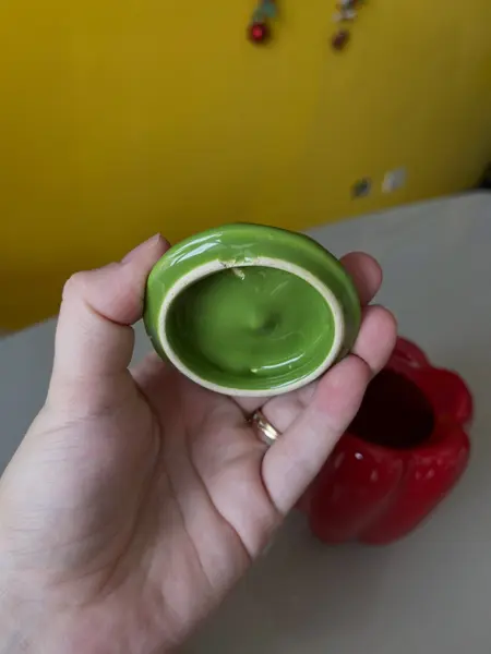 Foto de um(a) ​Pote com tampa em cerâmica formato pimentão, da categoria de Garrafas, potes e jarros. Pote com tampa em cerâmica. Possui lascado interno na tampa como mostrado nas fotos. Medidas: 12x10cm. Mostrado de uma perspectiva diferente. Vendido no marketplace Trésors.