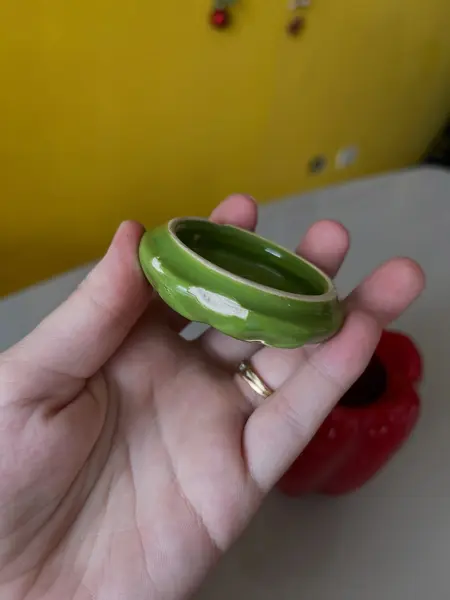 Foto de um(a) ​Pote com tampa em cerâmica formato pimentão, da categoria de Garrafas, potes e jarros. Pote com tampa em cerâmica. Possui lascado interno na tampa como mostrado nas fotos. Medidas: 12x10cm. Mostrado de uma perspectiva diferente. Vendido no marketplace Trésors.