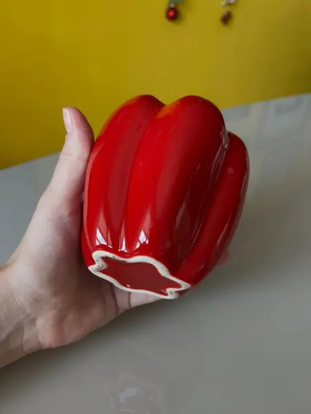 Foto de um(a) ​Pote com tampa em cerâmica formato pimentão, da categoria de Garrafas, potes e jarros. Pote com tampa em cerâmica. Possui lascado interno na tampa como mostrado nas fotos. Medidas: 12x10cm. Mostrado de uma perspectiva diferente. Vendido no marketplace Trésors.