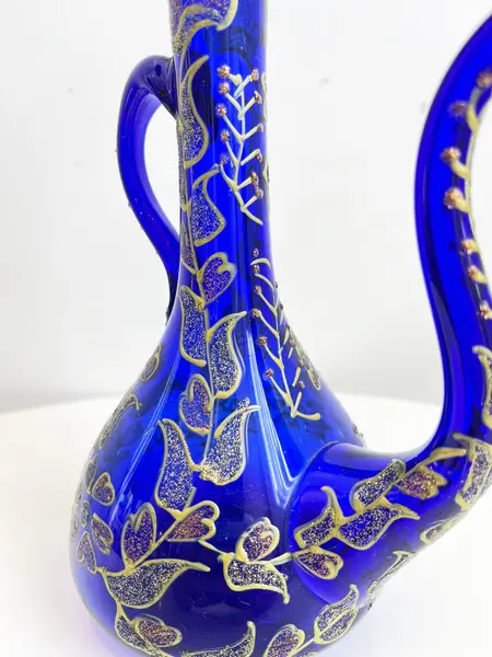 Foto de um(a) ​Jarra oriental em vidro azul, da categoria de Garrafas, potes e jarros. Jarra oriental em vidro azul, pintada a mão. Mínimas marcas do tempo e uso. Medidas: 25x11cm. Mostrado de uma perspectiva diferente. Vendido no marketplace Trésors.