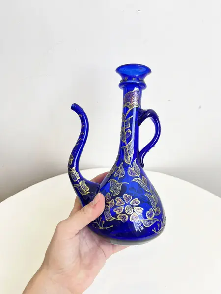 Foto de um(a) ​Jarra oriental em vidro azul, da categoria de Garrafas, potes e jarros. Jarra oriental em vidro azul, pintada a mão. Mínimas marcas do tempo e uso. Medidas: 25x11cm. Mostrado de uma perspectiva diferente. Vendido no marketplace Trésors.