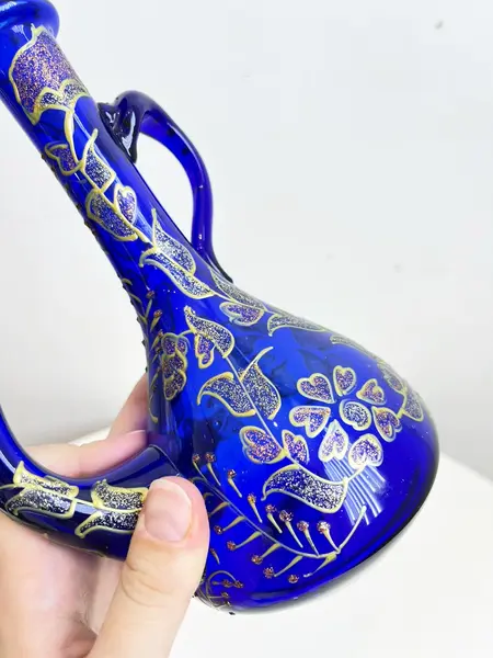 Foto de um(a) ​Jarra oriental em vidro azul, da categoria de Garrafas, potes e jarros. Jarra oriental em vidro azul, pintada a mão. Mínimas marcas do tempo e uso. Medidas: 25x11cm. Mostrado de uma perspectiva diferente. Vendido no marketplace Trésors.