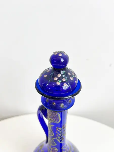 Foto de um(a) ​Jarra oriental em vidro azul, da categoria de Garrafas, potes e jarros. Jarra oriental em vidro azul, pintada a mão. Mínimas marcas do tempo e uso. Medidas: 25x11cm. Mostrado de uma perspectiva diferente. Vendido no marketplace Trésors.