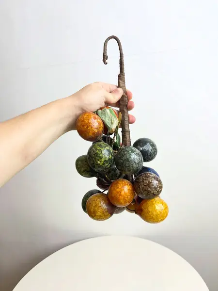 Foto de um(a) ​Grande cacho de frutas em resina e metal para pendurar, da categoria de Objetos decorativos. Grande cacho de frutas em resina e metal para pendurar. Possui marcas do tempo e uso como nas fotos. Medidas: 34x15cm. Mostrado de uma perspectiva diferente. Vendido no marketplace Trésors.