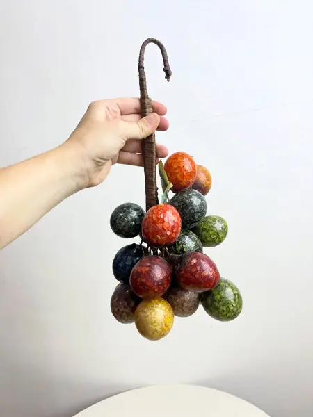 Foto de um(a) ​Grande cacho de frutas em resina e metal para pendurar, da categoria de Objetos decorativos. Grande cacho de frutas em resina e metal para pendurar. Possui marcas do tempo e uso como nas fotos. Medidas: 34x15cm. Mostrado de uma perspectiva diferente. Vendido no marketplace Trésors.