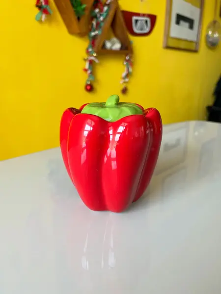 Foto de um(a) ​Pote com tampa em cerâmica formato pimentão, da categoria de Garrafas, potes e jarros. Pote com tampa em cerâmica. Possui lascado interno na tampa como mostrado nas fotos. Medidas: 12x10cm. Mostrado de uma perspectiva diferente. Vendido no marketplace Trésors.