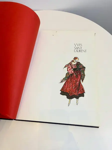 Foto de um(a) Livro capa dura Yves Saint Laurent 1983, da categoria de Livros. Maravilhoso livro capa dura em tecido, em inglês, de 1983. Marcas do tempo e uso. Mostrado de uma perspectiva diferente. Vendido no marketplace Trésors.
