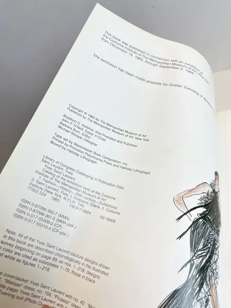 Foto de um(a) Livro capa dura Yves Saint Laurent 1983, da categoria de Livros. Maravilhoso livro capa dura em tecido, em inglês, de 1983. Marcas do tempo e uso. Mostrado de uma perspectiva diferente. Vendido no marketplace Trésors.